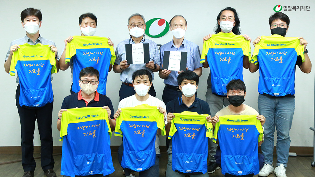 유니폼을 들고 있는 기브앤라이딩 라이더 및 밀알복지재단 관계자.jpg